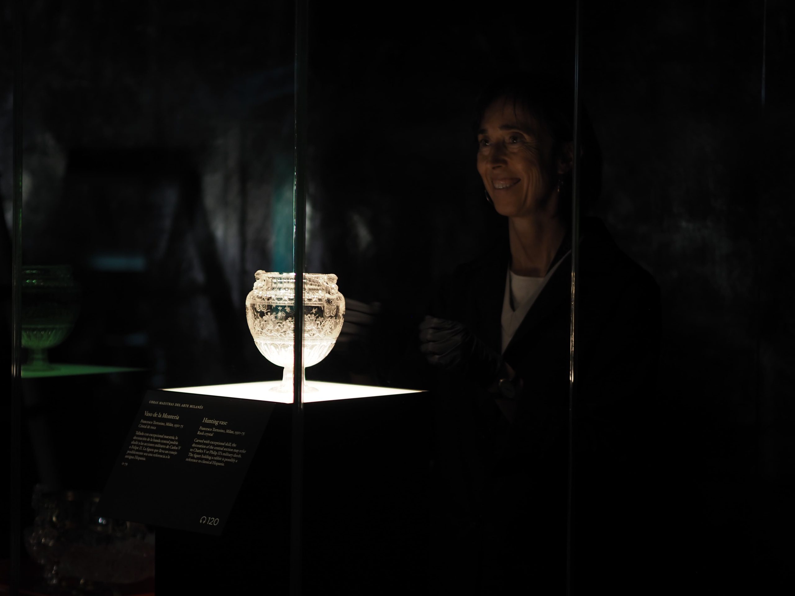 Visitante de museo y copa expuesta en vitrina iluminada