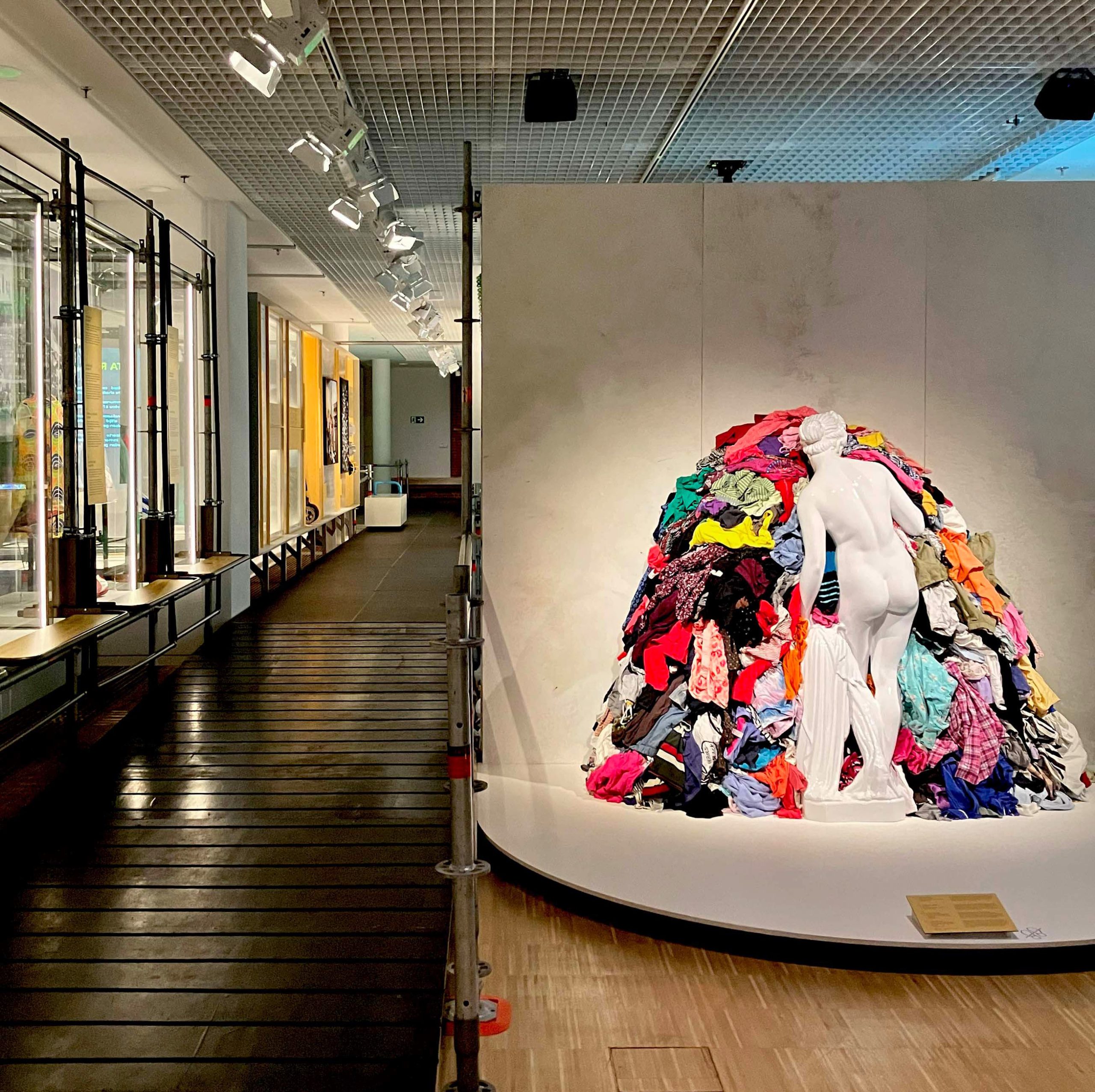 Escultura y montaña de residuos textiles en la exposición Throaway