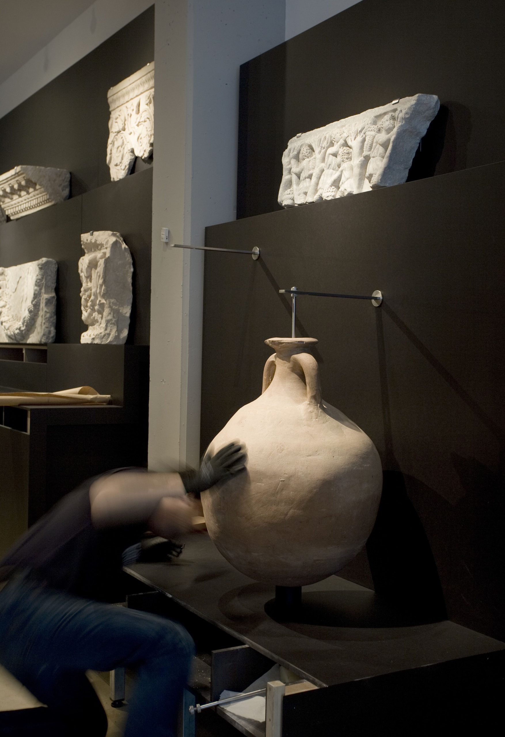 Técnico museográfico colocando vasija en soporte