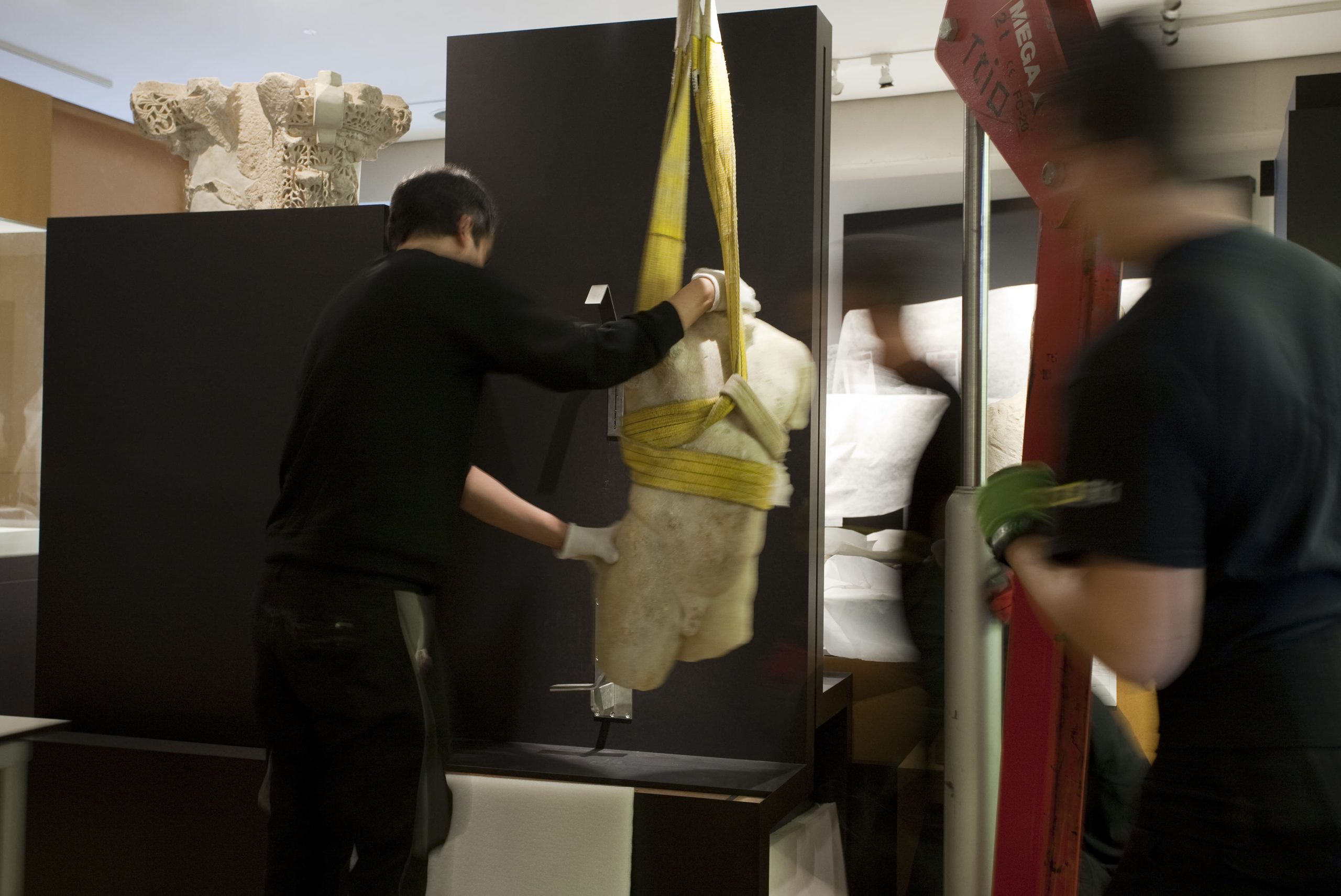 Técnicos museográficos manipulando escultura